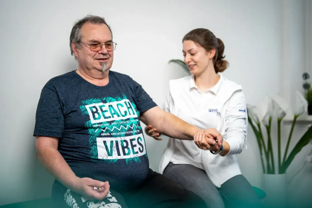 Ergotherapeutin übt mit einem Patienten Hand- und Armbewegungen